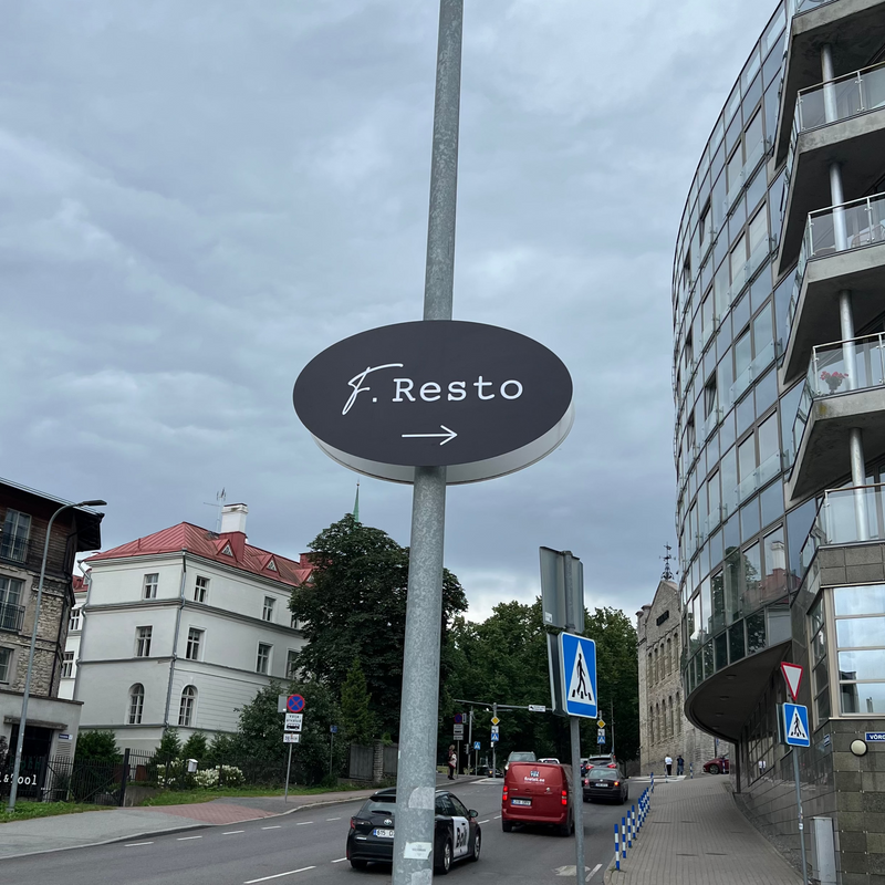 Street scene with a sign pointing to 'F. Resto' and modern buildings.