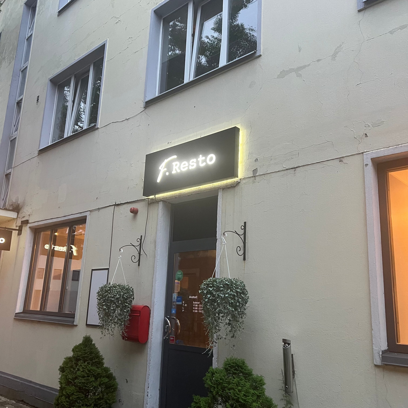 Building exterior with a neon sign reading 'Festo' above the entrance.